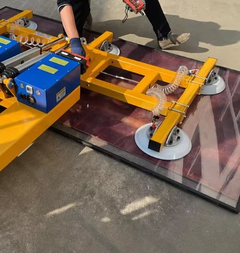 Forklift-mounted vacuum lifter holding a granite slab with four suction cups