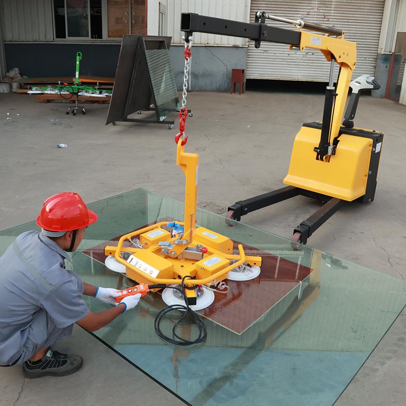X-frame vacuum lifter carrying a large glass panel in a workshop yard